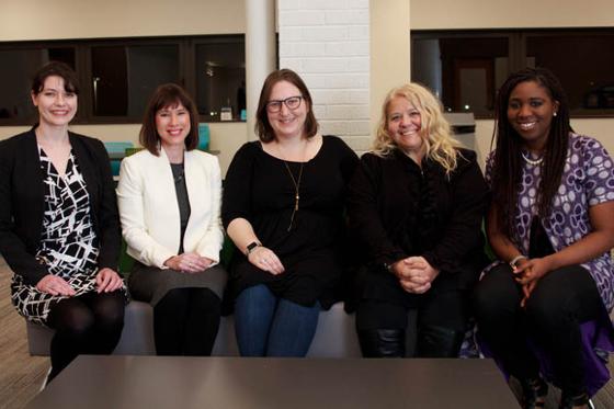 Photo of five women seated together, smiling